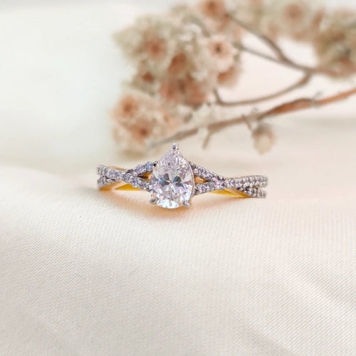Diamond ring with a pear-shaped center stone on a white background
