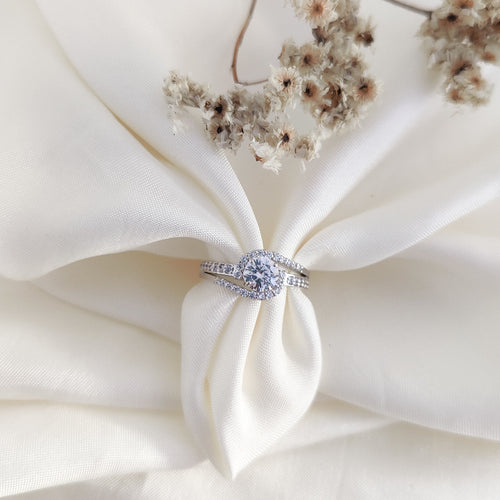 brilliant round-cut diamond simulant at the center, surrounded by a shimmering halo of CZ accents.