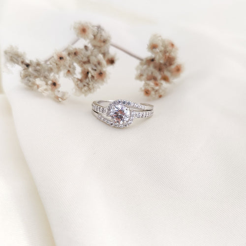brilliant round-cut diamond simulant at the center, surrounded by a shimmering halo of CZ accents.